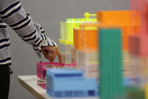A hand reaching out to point to colourful model buildings created by MSD students.