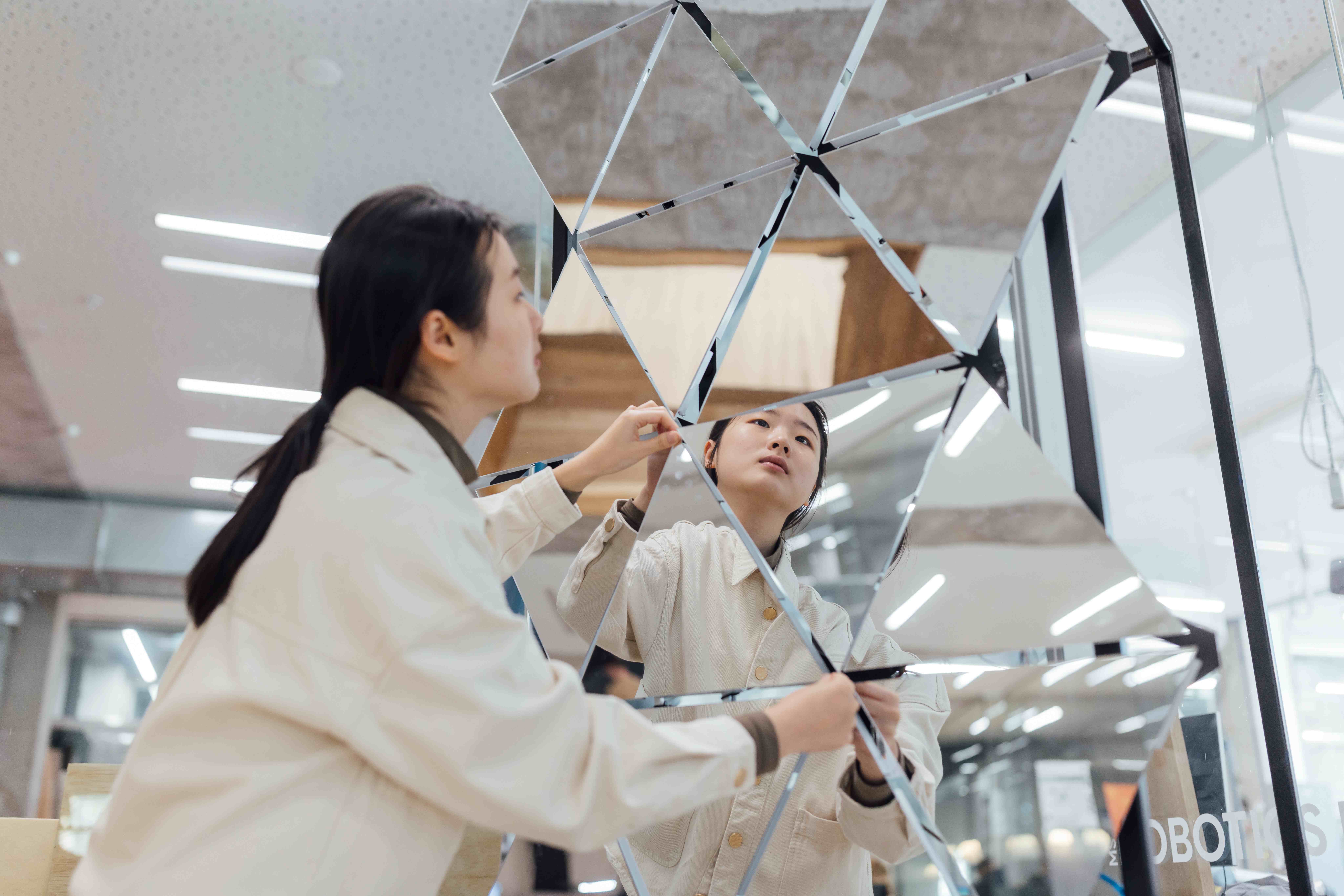 A student works with mirrors in the robotics lab