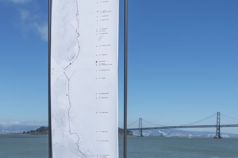 A white banner against a blue sky with a bridge in the background.