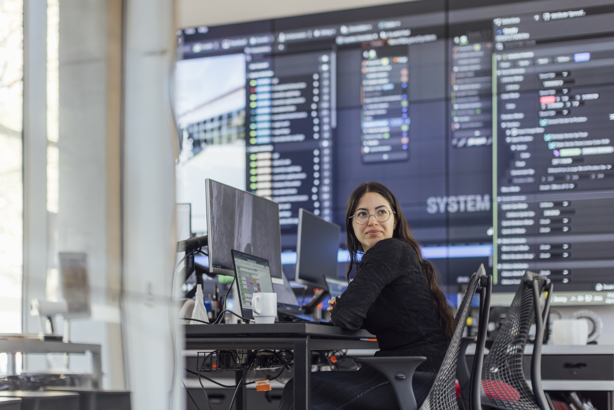 A person in front of a bank of digital screens