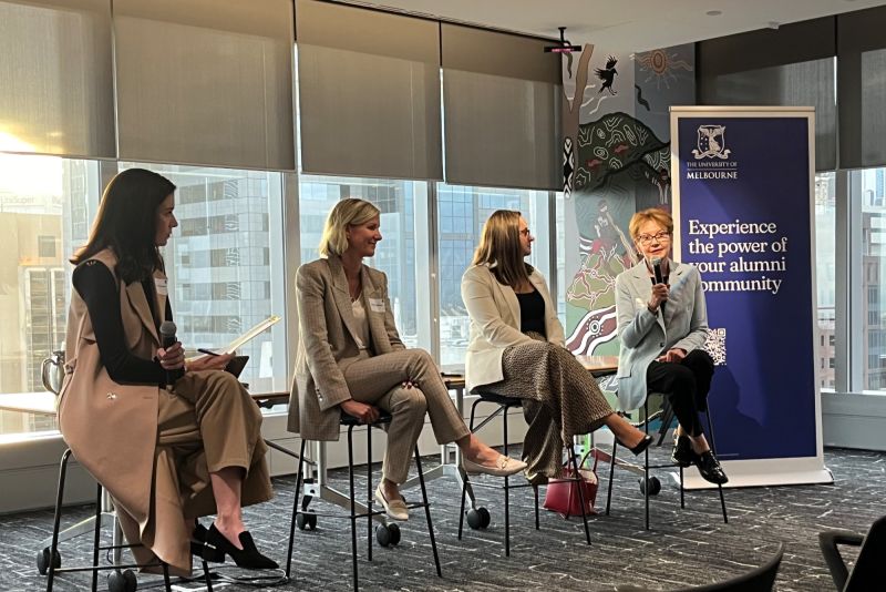 Four women on stools presenting to an audience