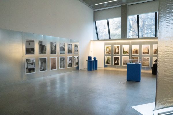 Image showcasing a corner of the exhibition, the walls are a reflective silver, with posters displayed. 