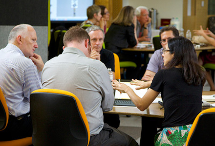 Academics and industry practitioners sitting at a table having a discussion.