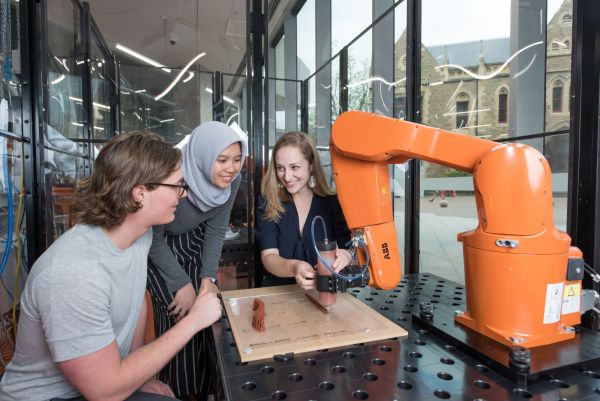 Meet Melbourne in Indonesia Three students look at a robotic arm