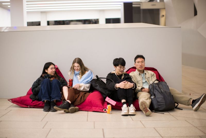 Four students sitting on beanbags against a white wall