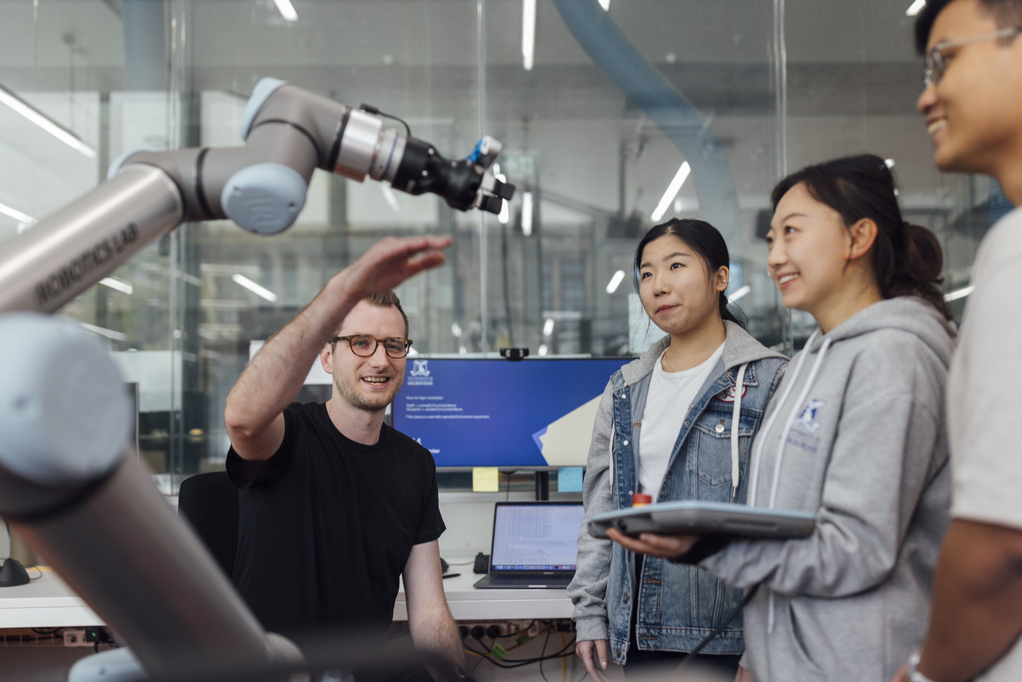 A lab technician demonstrating a robotic arm